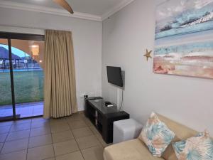 ein Wohnzimmer mit Couch und Flachbildfernseher in der Unterkunft 16 Cabanas Del Mar Winklespruit KZN South Coast in Kingsborough