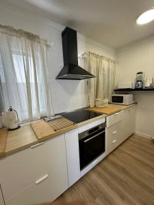 una cucina con armadi bianchi e un forno a piano cottura nero di Sunny Holidays in Casa Familiar Playa La Arena a Puerto de Santiago