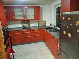 a kitchen with red cabinets and a stainless steel refrigerator at Ferienwohnung am See in Ostrach