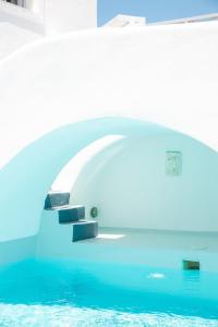 a room with a pool of water and a bridge at White Cave Villas in Oia