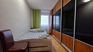 a small bedroom with a bed and a window at Niebieski Meander Pokoje blisko metra in Warsaw