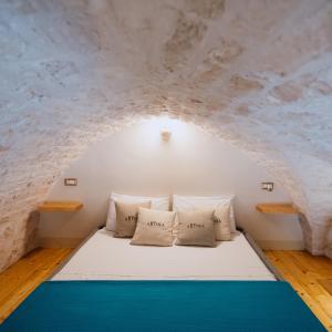 a bed in a room with a stone wall at AROMA luxury in Ostuni