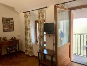 a room with a door and a television and a balcony at Casetta Fiabesca near Ivrea in Banchette
