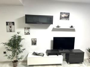 un soggiorno con TV e divano bianco di Bonita casa adosada a Cordoba