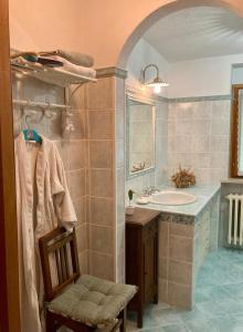 a bathroom with a sink and a mirror and a chair at Casetta Fiabesca near Ivrea in Banchette +11 photos