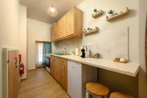 a kitchen with wooden cabinets and a counter top at Petite Apt with patio at Garitsa! in Corfu