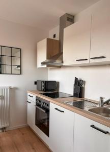 a kitchen with white cabinets and a sink at Charmante Schlossblick Wohnung in Aschaffenburg