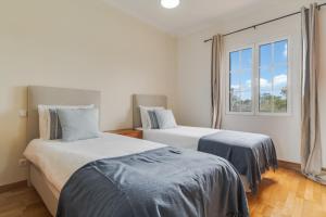two beds in a room with a window at Porto Moniz Yellow House in Porto Moniz