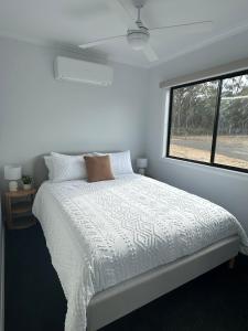 Un dormitorio blanco con una cama y una ventana. en The Wellsford Cabin - Retreat & Holiday With Your Horse, en Goornong