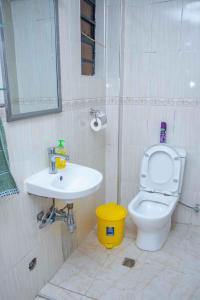 a bathroom with a white toilet and a sink at MariKings place in Ruaka