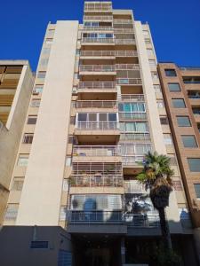 a tall building with a palm tree in front of it at Habitación silenciosa Nº1 en Dpto Compartido in Cordoba