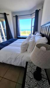 a bedroom with a large white bed with a window at 7 Uvongo Breeze in Margate +25 photos