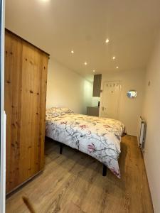a bedroom with a bed and a wooden cabinet at Ensuite double Room near ExCeL London in London