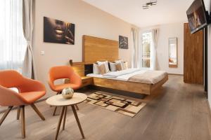a bedroom with a bed and two orange chairs at Hotel Vier Jahreszeiten an der Therme & Kliniken Bad Krozingen Nähe Freiburg & Schwarzwald Ideal für Wellness Kur & Business Ausflüge 24h Check In- WLAN & Parken gratis in Bad Krozingen