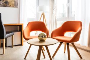 two orange chairs and a table in a room at Hotel Vier Jahreszeiten an der Therme & Kliniken Bad Krozingen Nähe Freiburg & Schwarzwald Ideal für Wellness Kur & Business Ausflüge 24h Check In- WLAN & Parken gratis in Bad Krozingen +37 photos