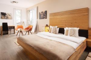 a bedroom with a large bed with a wooden headboard at Hotel Vier Jahreszeiten an der Therme & Kliniken Bad Krozingen Nähe Freiburg & Schwarzwald Ideal für Wellness Kur & Business Ausflüge 24h Check In- WLAN & Parken gratis in Bad Krozingen