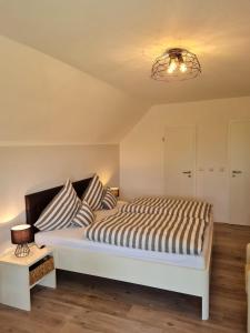 1 dormitorio con 1 cama blanca grande con almohadas a rayas en Ferienhaus Naase App 4, en Norderney