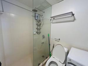 a bathroom with a toilet and a glass shower at The Mindful Home - 2BR Cozy Condo near NAIA in Manila +5 photos