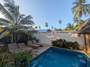 a villa with a swimming pool and palm trees at Zuzanu house in Nungwi