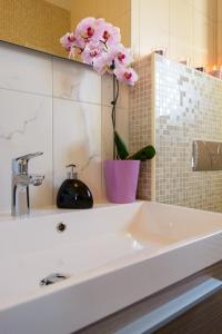 a white sink in a bathroom with a vase with a flower at Apartments Topli Bok in Trogir