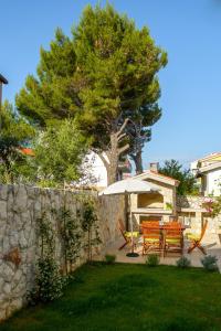 a backyard with a table and chairs and a tree at Apartments Topli Bok in Trogir