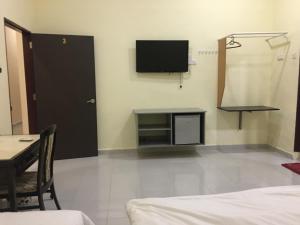 a room with a tv on the wall and a table at Bonsai Homestay Kluang - Meranti in Kluang