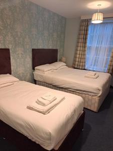 two beds in a hotel room with towels on them at Luther King House in Manchester