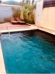 a swimming pool with two benches next to a house at Beautiful house Juquehy in São Sebastião