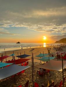 a beach with umbrellas and people on the sand at Beautiful house Juquehy in São Sebastião