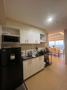 a kitchen with white cabinets and a black refrigerator at Avida Towers Condo Near Peoples Park and Roxas Night Market in Davao City