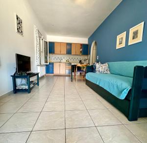 a living room with a blue couch and a kitchen at Andros Eco Home in Gavrio