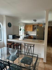 a kitchen with a glass table and chairs and a counter at Casa Estrelinha Vilamoura in Quarteira