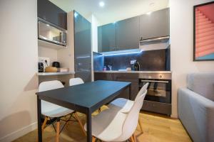 une cuisine avec une table noire et des chaises blanches dans l'établissement CIA - Parc Monceau 4P, à Paris