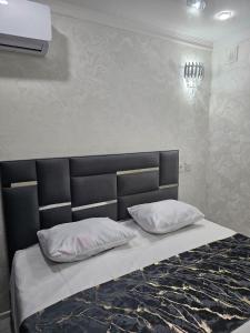 a bed with a black headboard and white pillows at Апарт Отель MaRi in Shymkent