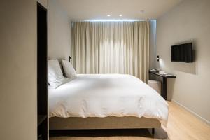a bedroom with a large white bed and a television at Istoire in Bruges
