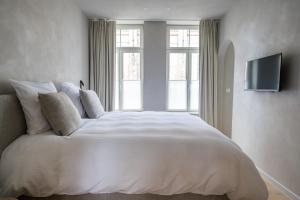a bedroom with a white bed with a television on the wall at Istoire in Bruges