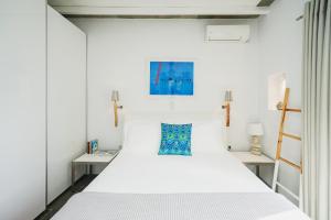 a bedroom with a white bed and two tables at Villa Arades Sifnos with Private Pool in Apollonia
