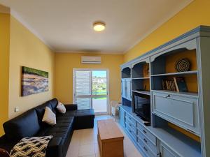 a living room with a couch and a tv at 4º5 Edificio Mar - Casas & Papeis in Armação de Pêra
