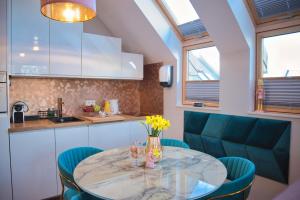 a kitchen with a glass table and blue chairs at Apartament Jastrzębia Góra in Jastrzębia Góra