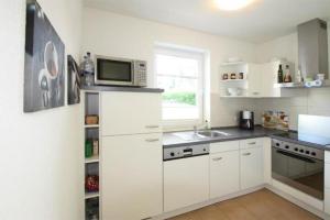 a kitchen with white cabinets and a microwave at Hanne-Hus in Kühlungsborn
