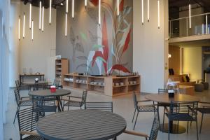 a restaurant with tables and chairs and a mural at Ramada Encore Ponta Grossa in Ponta Grossa