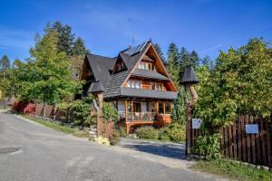 a large wooden house with a black roof at U Pabinów in Kościelisko