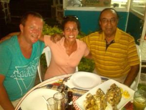drie mensen aan een tafel met een bord eten bij Auberge Etiennette in Trou dʼ Eau Douce