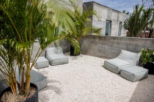 a patio with white pillows and palm trees in front of a building at Sojourn in Tumbak Bayuh