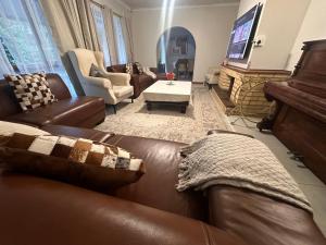 a living room with a leather couch and a piano at The Aurum guesthouse in Durban