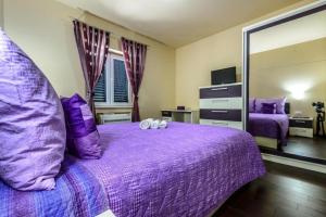 a bedroom with a purple bed with two pillows at Countyside Retreat Six Bedroom Villa with Pool in Gruda +25 photos