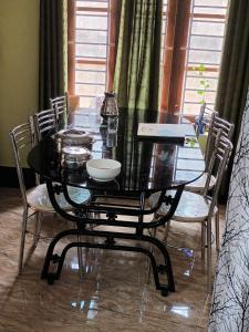 un tavolo da pranzo con sedie e un tavolo in vetro nero di Villa Florence Homestay Varkala Cliff a Varkala