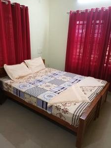 Posto letto in camera con tende rosse. di Villa Florence Homestay Varkala Cliff a Varkala