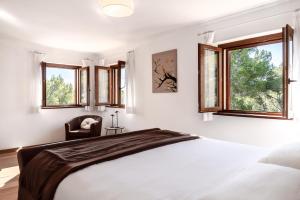a bedroom with a bed and two windows at Es Puig De Portocolom in Cala Murada