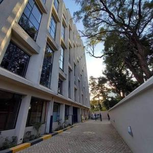 a large building with a tree next to a street at A modern affordable stylish bedsitter centrally located in nairobi in Nairobi +29 photos